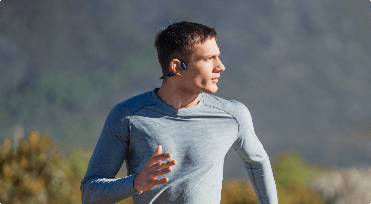 Un coureur portant le casque de sport à conduction osseuse OpenRun bleu de Shokz. Toute la liberté des oreilles.